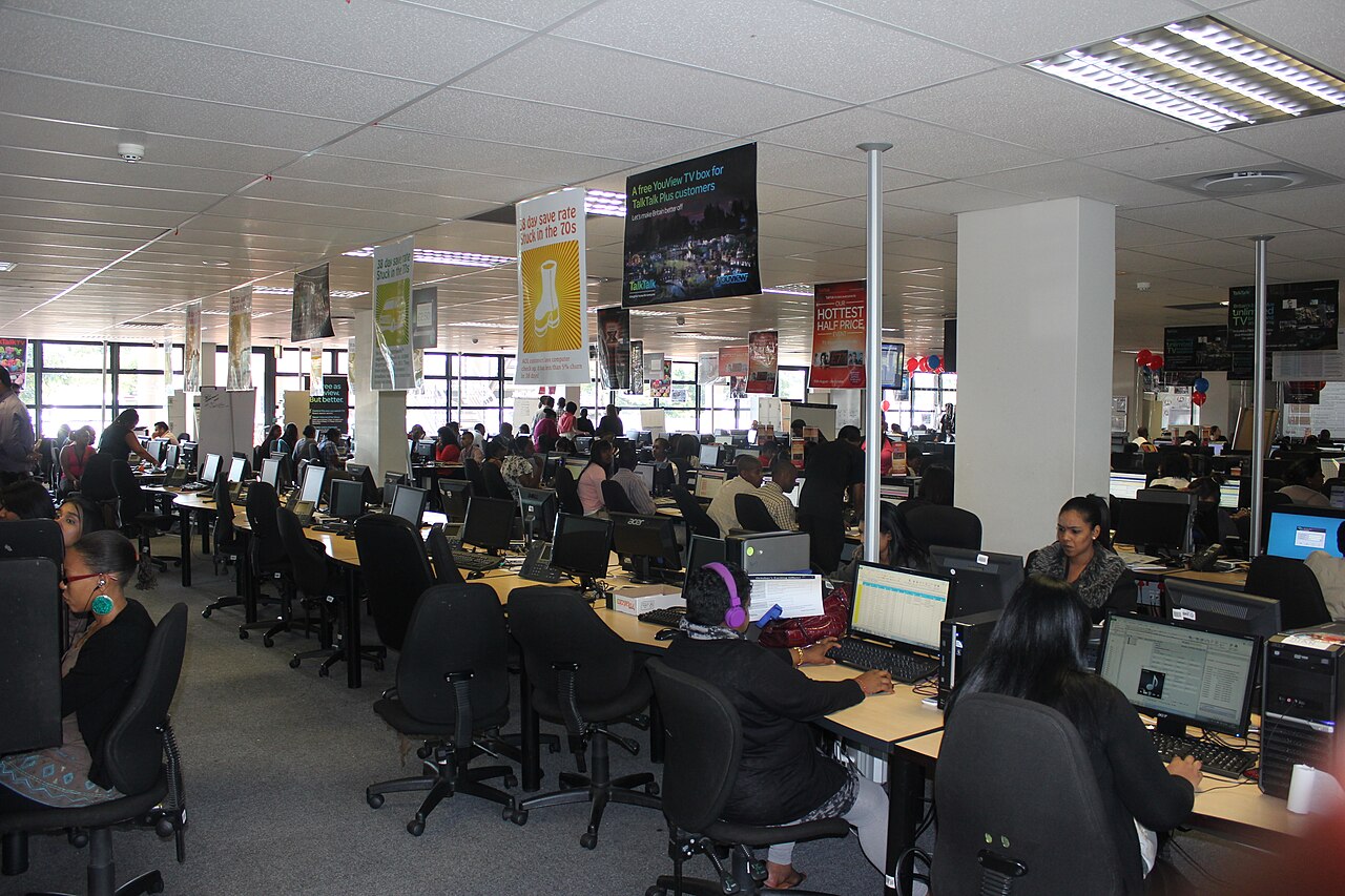 A call centre floor with rows of operators at computer desks answering calls
