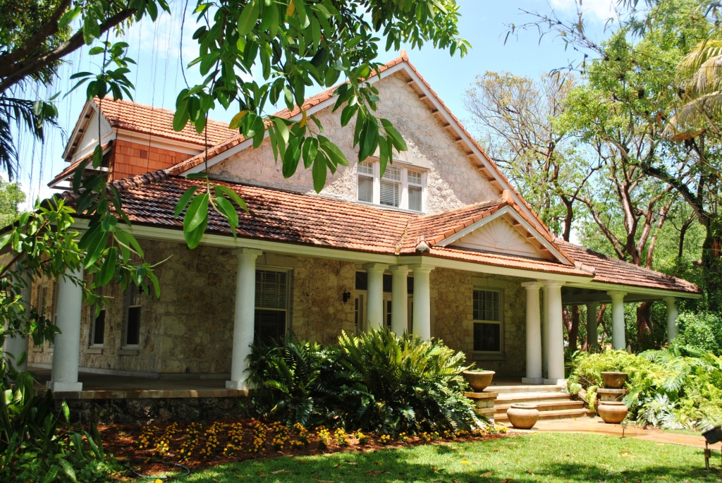 A stone house with a red tile roof and a columned porch in Coral Gables, Florida