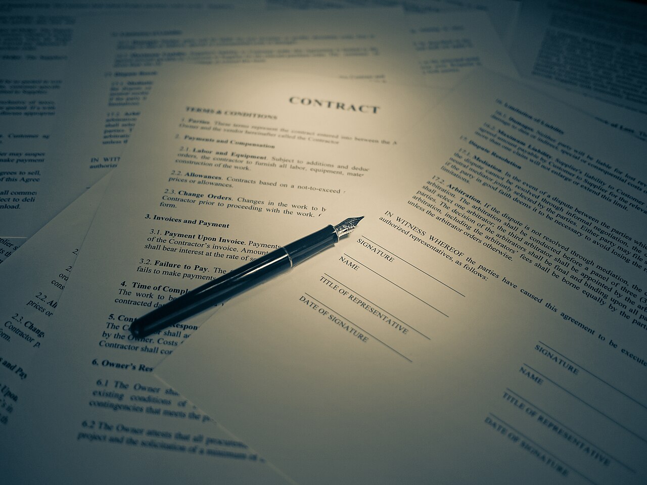 Contract paperwork spread on a desk with a fountain pen resting on the signature page